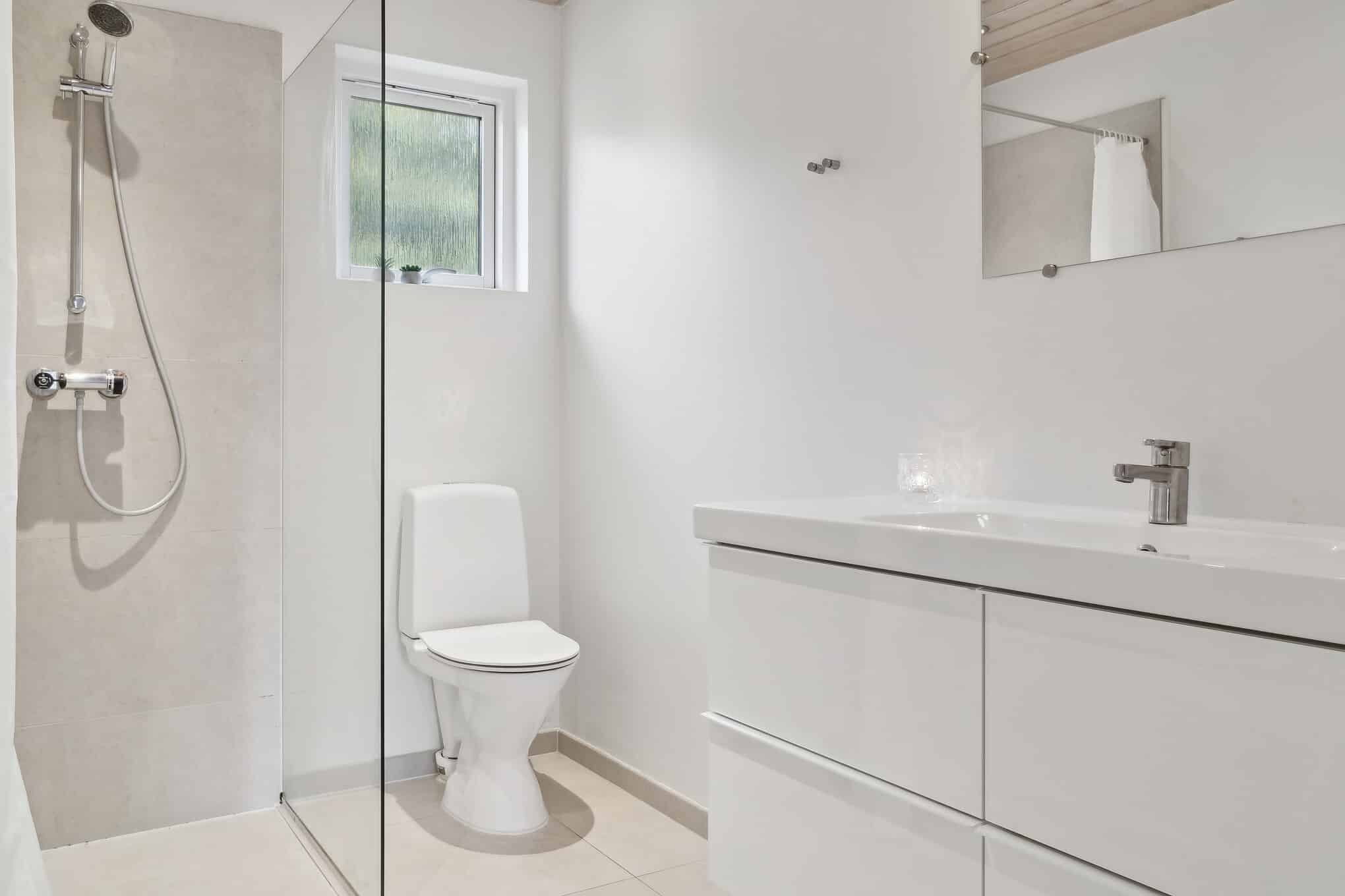 Badeværelse med hvid håndvask, toilet og bruseplads