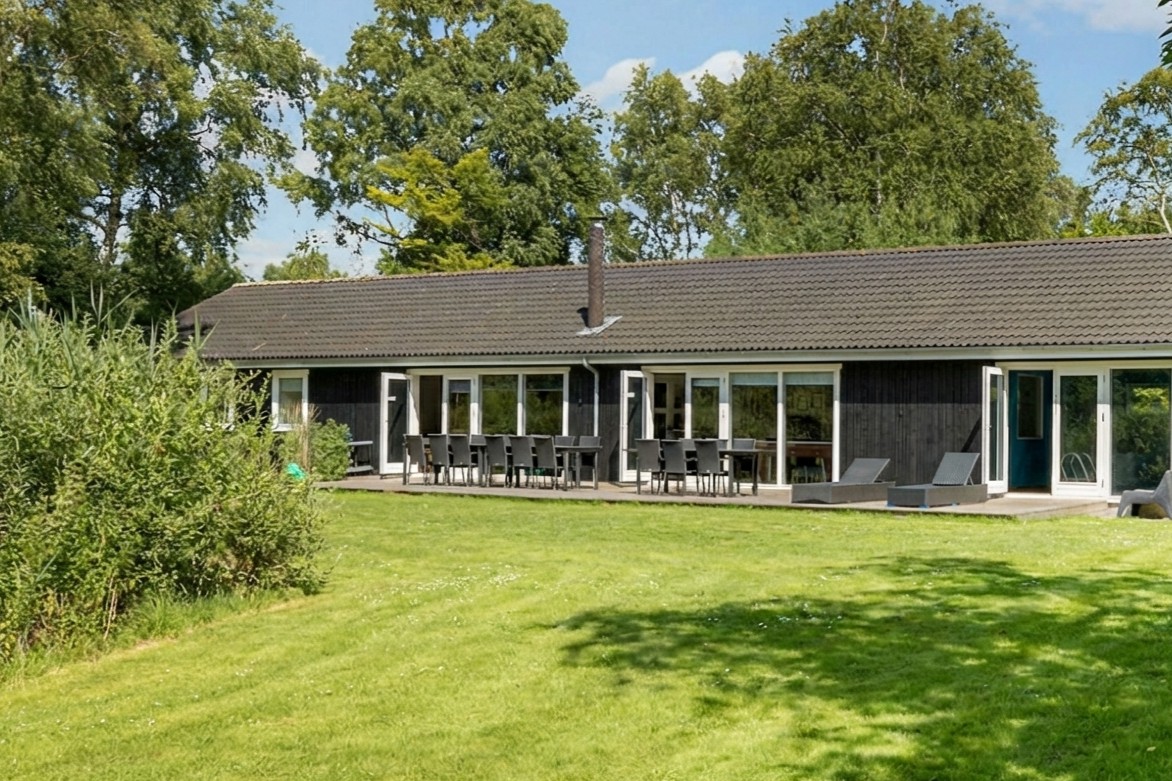 Husets facade, terrasse og grønne plæne